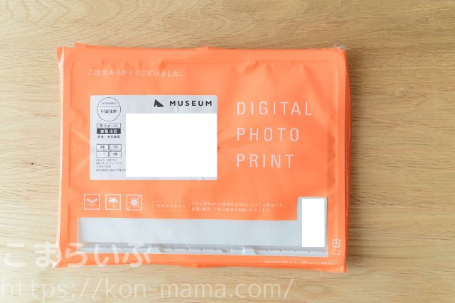 MUSEUMフォトブックの外装パッケージ。オレンジ色の封筒にDIGITAL PHOTO PRINTと表記
