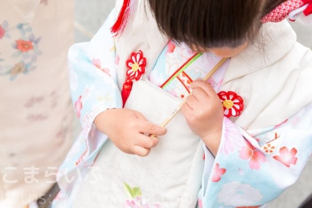 七五三で着物を着た女の子がおみくじを手に持つ様子。