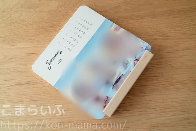 しまうまカレンダーを木製スタンドに立てかけた状態を斜め上から撮影した写真。スタンドの溝にカレンダーがしっかり収まっている様子がわかる。