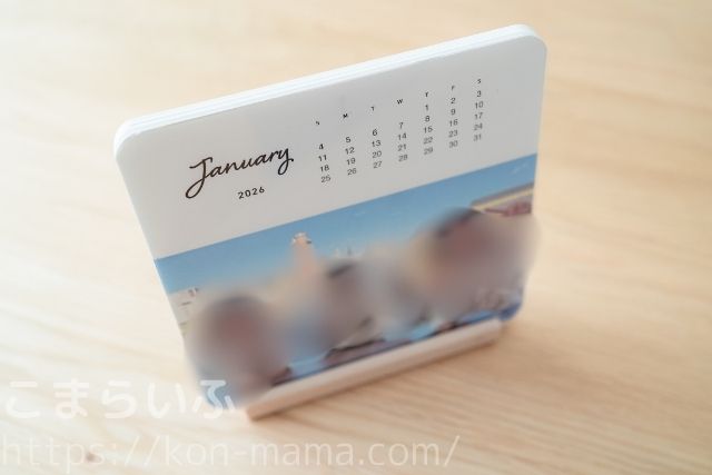 木製スタンドに1枚のカレンダーを立てた状態の写真。アクリルプレートと組み合わせると安定して飾れる。