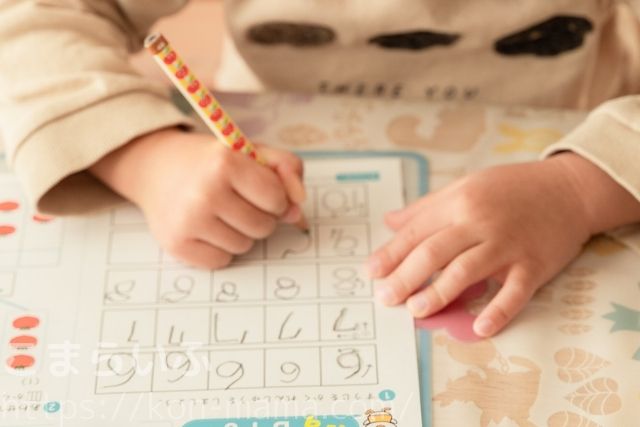 年長の入学準備で紙プリントを使って数字を書く練習をする子ども