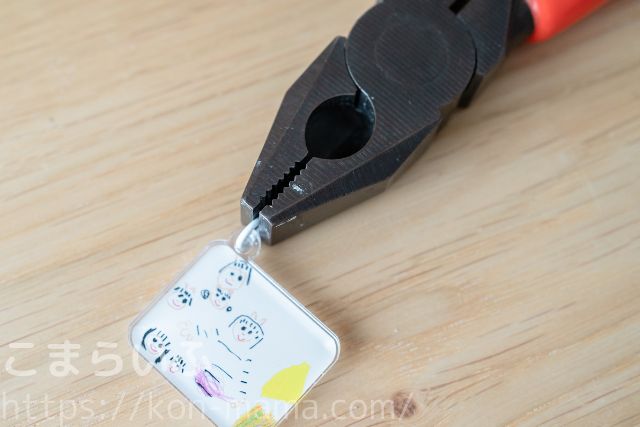 ペンチで丸カンを取り付けている様子